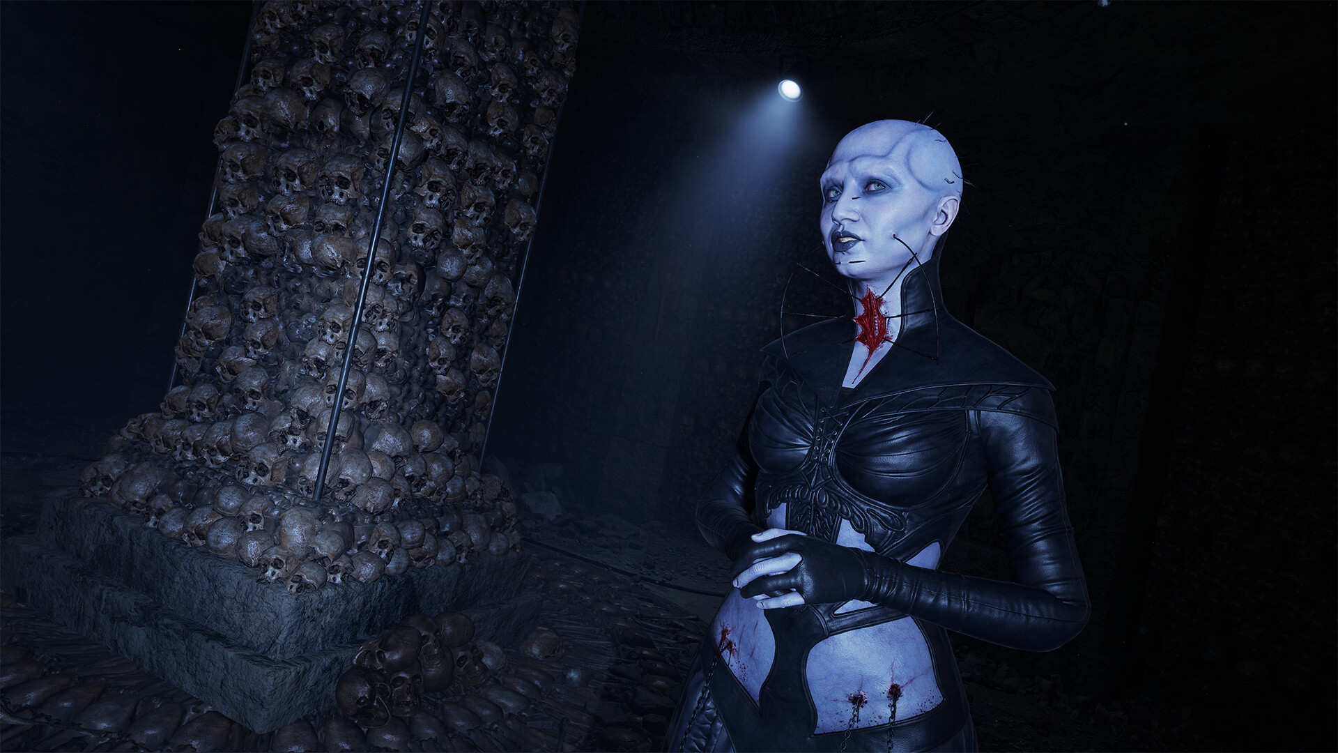 A pale Cenobite with metal pins and a dark leather outfit stands beside a pillar covered in skulls in Hellraiser: Revival.